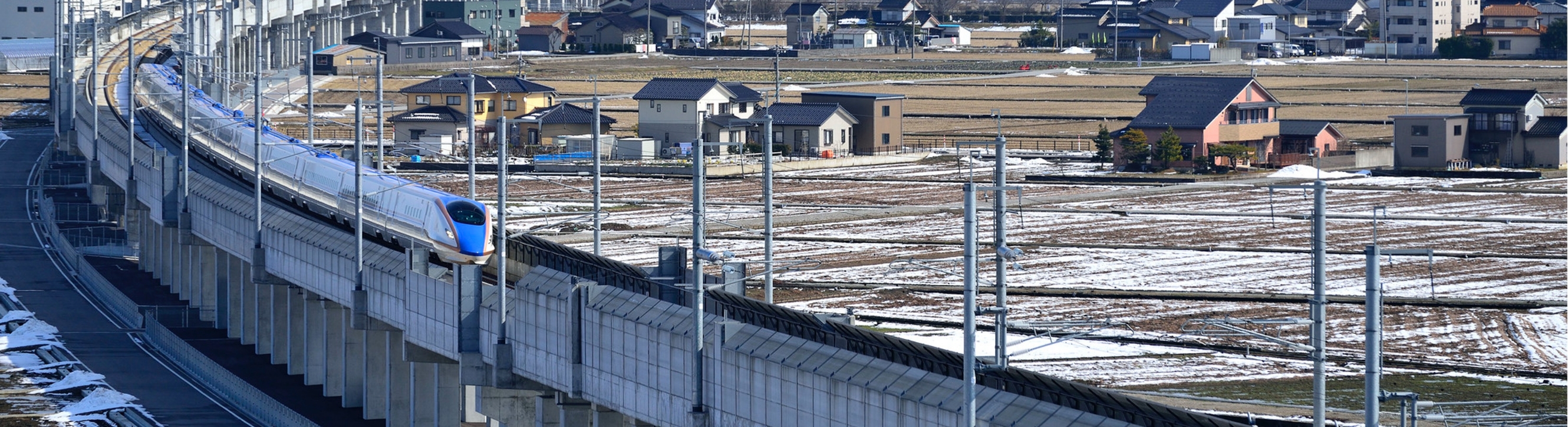 雪が積もった田園風景を走る新幹線